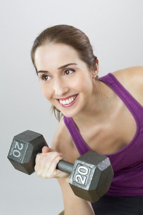 A girl holding dumbbells is doing weight loss exercise